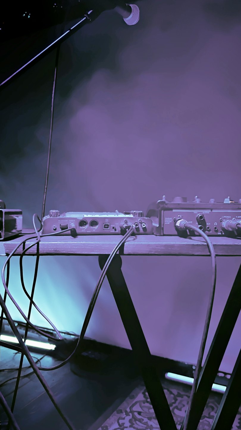 Audio mixing equipment and cables on a table for live music.