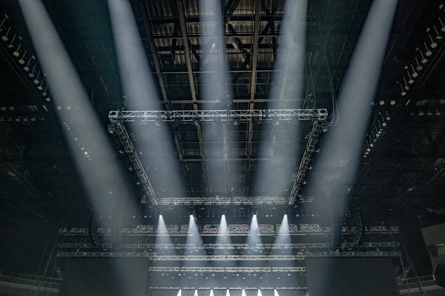 Empty concert stage with powerful lights shining upward into rafters.